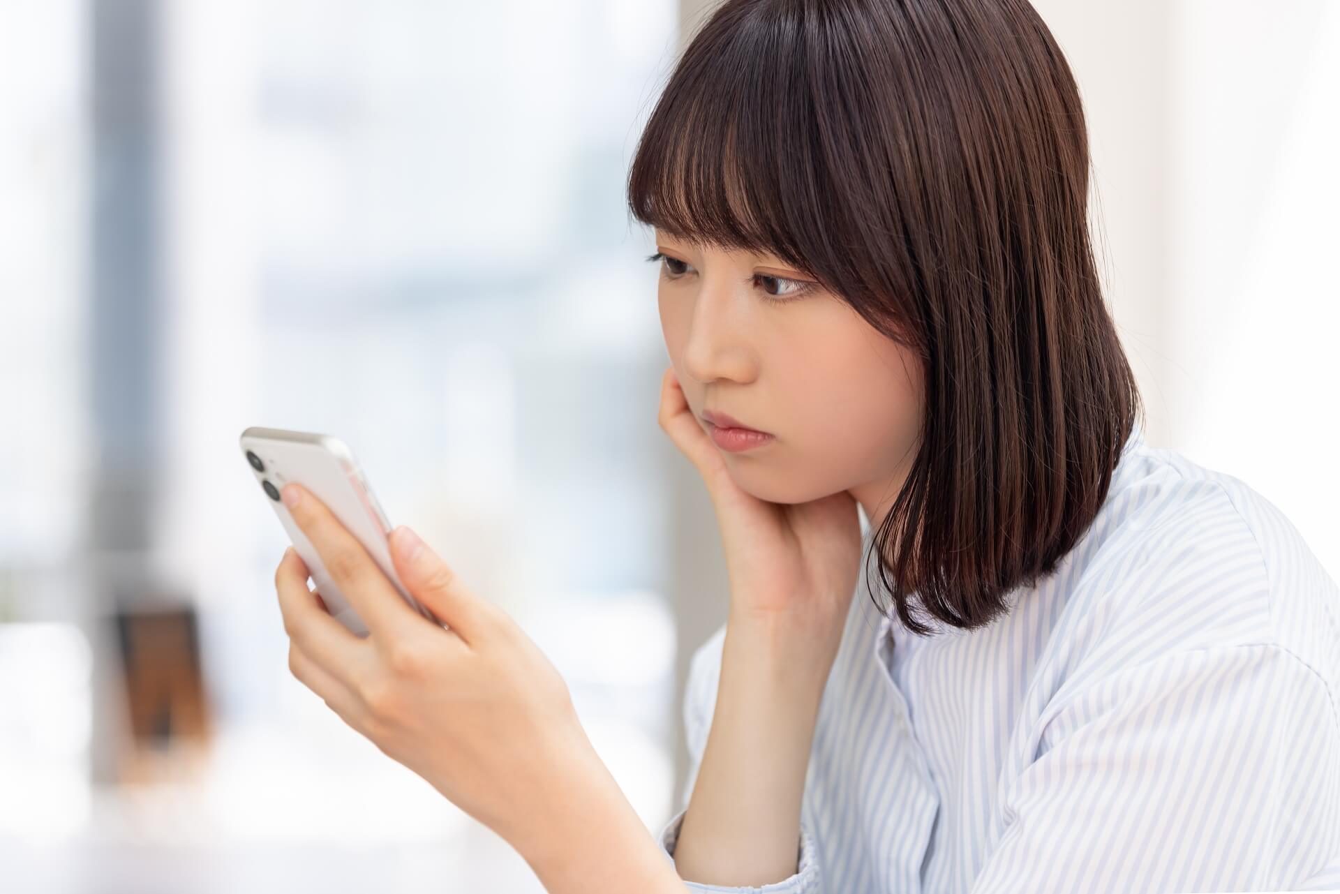 スマホを見て考える若いビジネスウーマン
