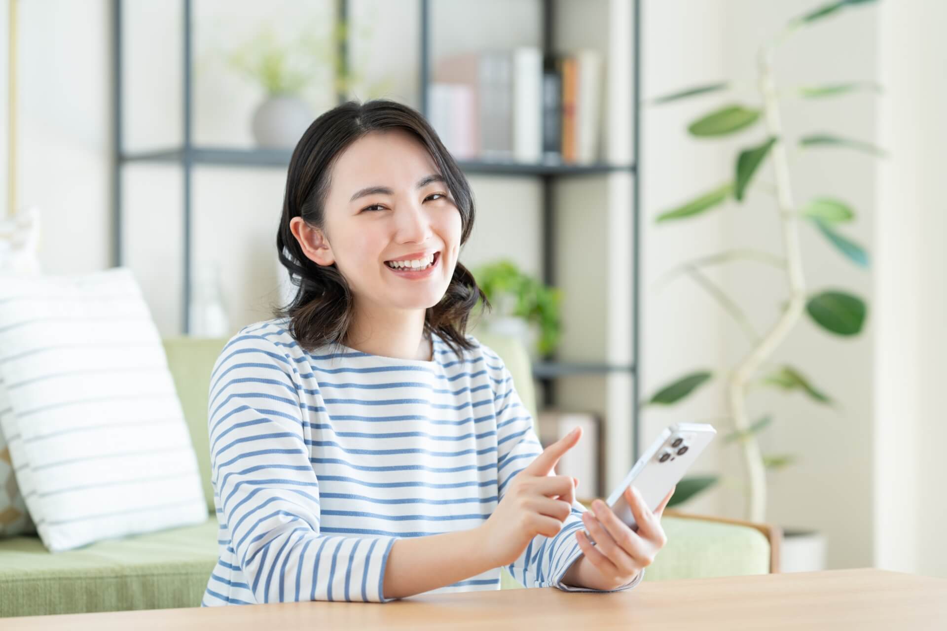 リビングでスマホを見る若い女性
